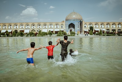 四个孩子白天在水泥建筑物旁边的水面上玩耍